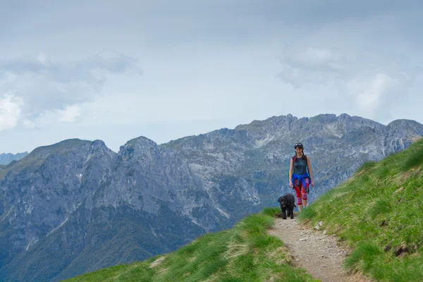 Vrouw met haar hond wandelen op het bergpad — Stockfoto