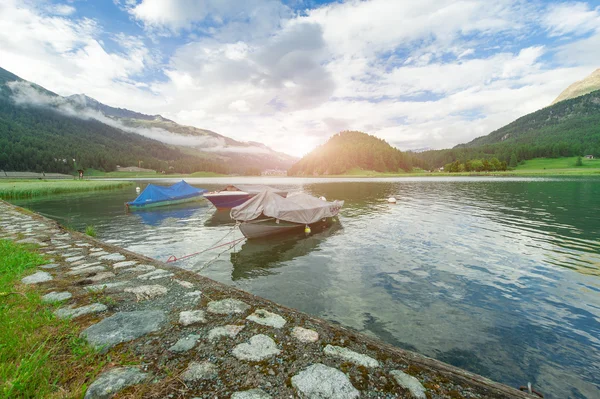 Meer met boten tijdens de zonsondergang in de Engadin vallei in Zwitserland — Stockfoto