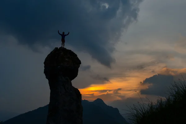 Man conquers the top of a mountain after a hard climb at sunset — Stock Photo, Image