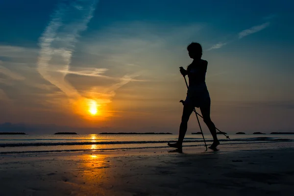 Kobieta, uprawiania nordic walking po plaży o wschodzie słońca w późnym — Zdjęcie stockowe