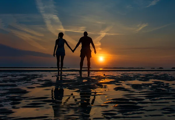 Couple hand in hand towards the sea in a dawn late summer — Stock Photo, Image