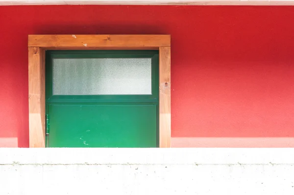 Зелені зачинені двері проти червоної стіни — стокове фото