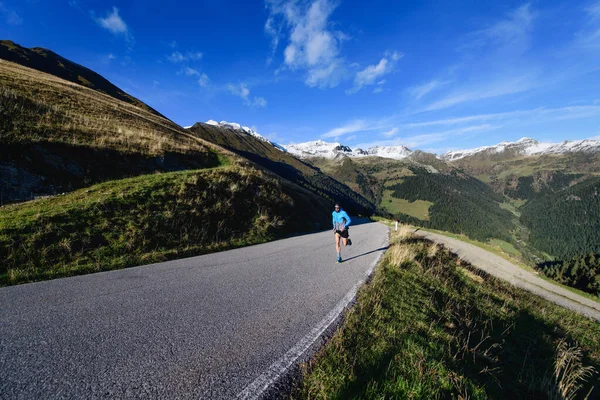 トレーニング中の孤独なランナーとアスファルト山道 — ストック写真