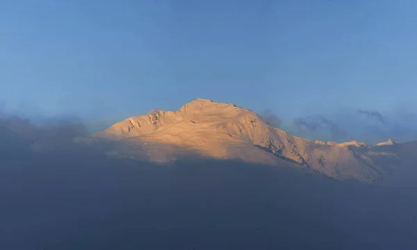 Pico Coberto Neve Emerge Das Nuvens Coloridas Sol Poente — Fotografia de Stock