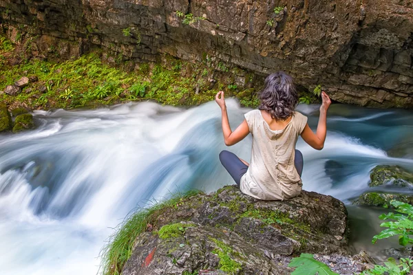 Dziewczyna robi joga w pobliżu narodziny rzeka ze skały — Zdjęcie stockowe