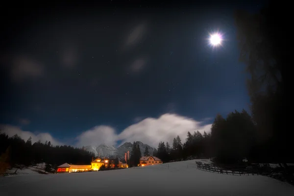 在星光灿烂的夜晚，月亮与雪房子 — 图库照片