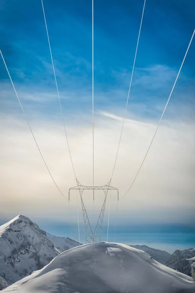Pylonen bedekt met sneeuw in het hooggebergte dragen energie naar beneden — Stockfoto
