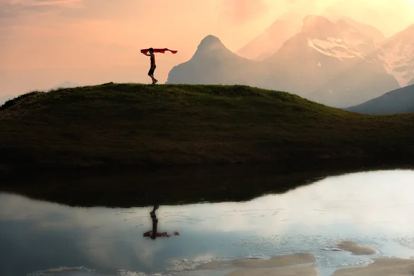 Menina corre nas montanhas com um lenço na mão ao pôr do sol — Fotografia de Stock