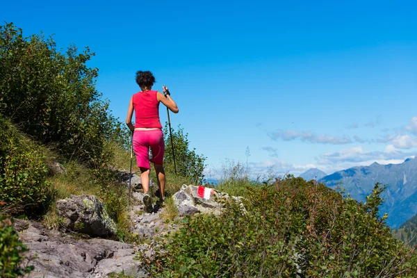 Meisje wandelingen in de bergen met stokken. — Stockfoto