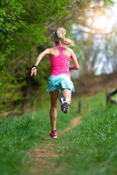 Atleta bionda che corre in un sentiero nel bosco — Foto Stock
