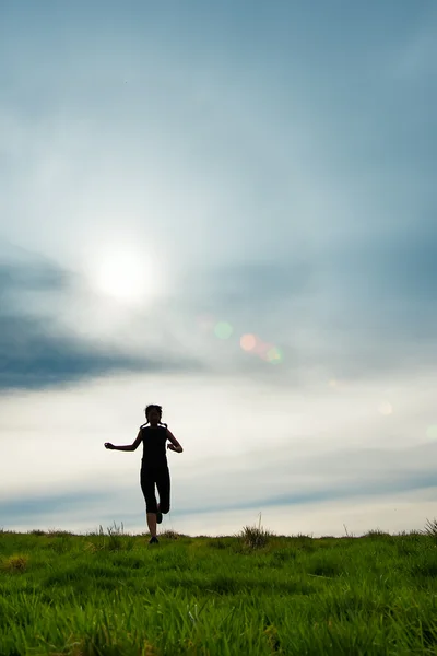 Silueta de una chica con trenzas corriendo en un prado —  Fotos de Stock