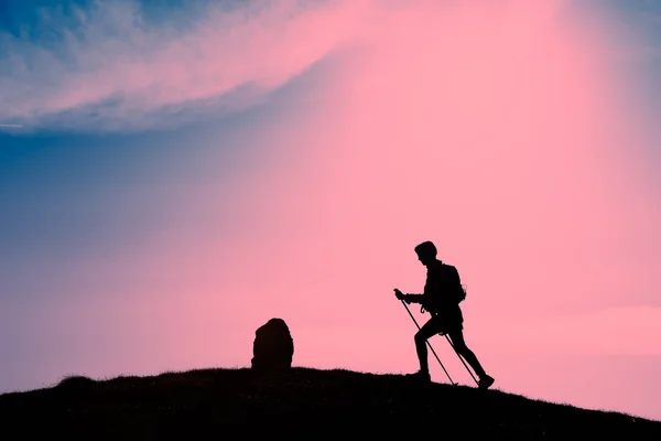 Silhouette eines Mädchens, das Trekking in einem rosa Sonnenuntergang macht — Stockfoto