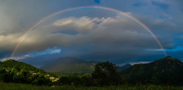 夕暮れ時の山の小さな村上本物の虹 — ストック写真