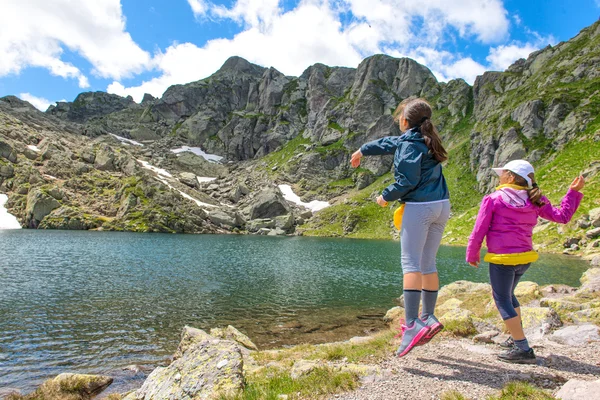 Two girls throw rocks in a mountain lake — Stock Photo, Image