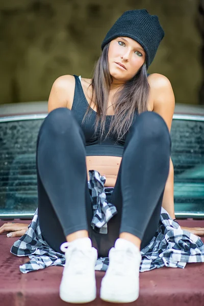 Girl sitting on an old car — Stok fotoğraf