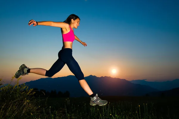 Chica saltando al atardecer en las montañas — Foto de Stock