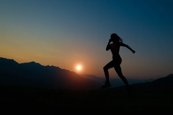 夕暮れ時、山で走っている女性のシルエット — ストック写真