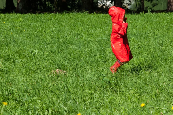 Petit enfant saute avec un imperméable rouge et des bottes rouges — Photo