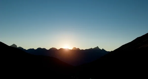 Auringonlasku pimeällä vuorella siluetissa — kuvapankkivalokuva