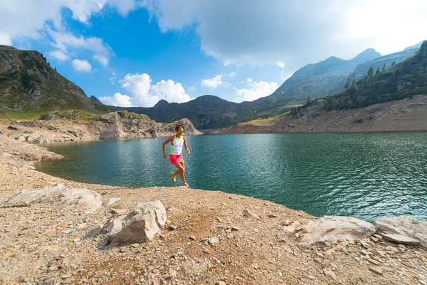 Racing action of a woman near an alpine lake — Stock Photo, Image