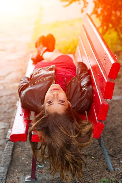 Ng girl lying on a red bench with long hair back — Stock Photo, Image