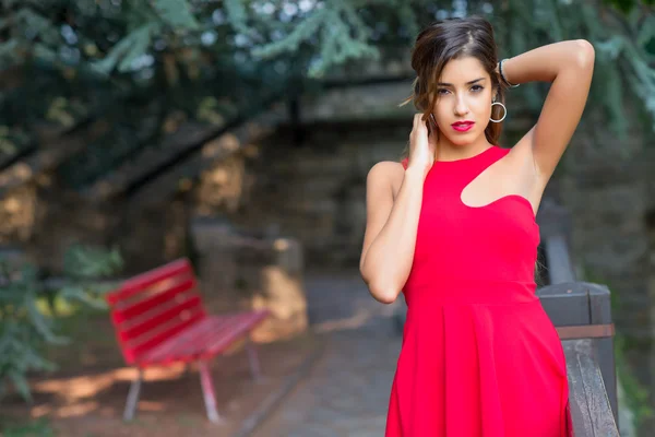 Beautiful girl with red dress holding her hair with her hands — Stockfoto