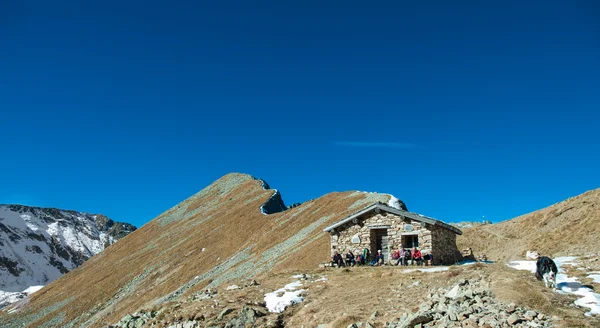 Group of trekkers rest in a hut under the mountain with dog — Stock Photo, Image