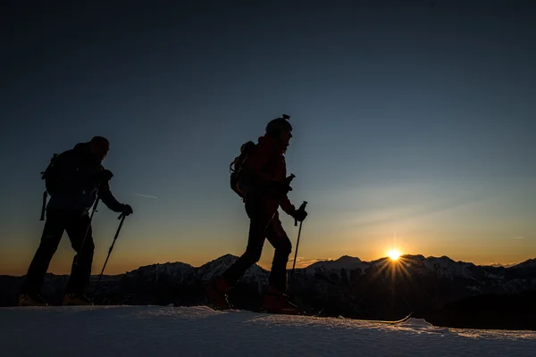 Ski bergbeklimmers klimmen bergen met ski in de avond bij zonnen — Stockfoto