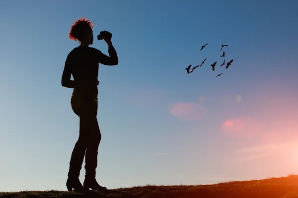 Mulher com câmera de vídeo filmando pássaros no céu — Fotografia de Stock