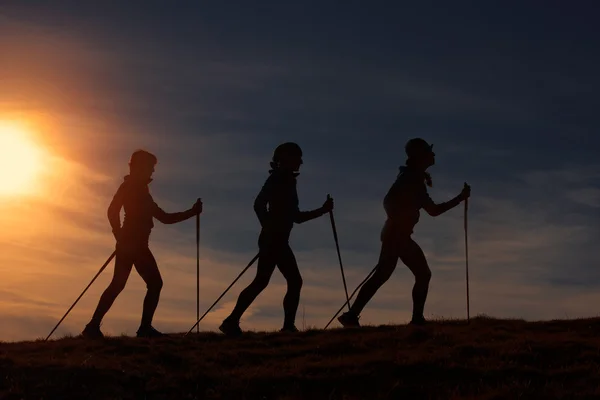 Nordic walking w sylwetka w zachód słońca — Zdjęcie stockowe