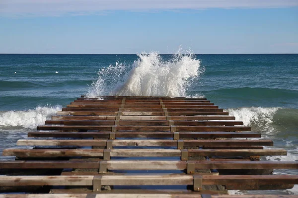 Deniz dalgaları bir kaldırıma çarpıyor.