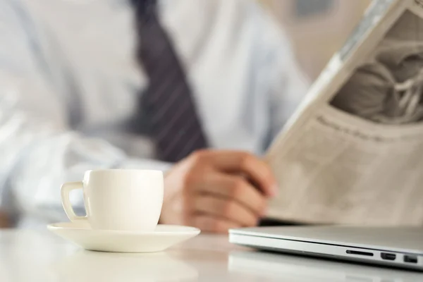 Filiżanka kawy z biznesmenem czytania gazety na tle — Zdjęcie stockowe