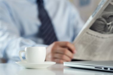 Sabah haber okuma işadamı ile worktable üzerinde kahve fincan