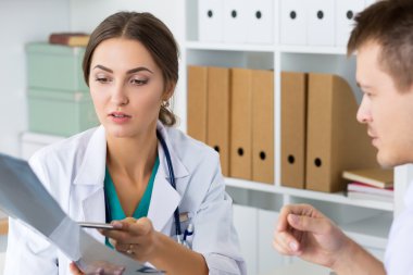 Kadın doktor hastasına bir şeyler gösteriyor.