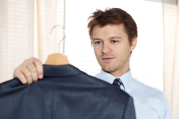 Hombre de negocios sosteniendo su abrigo y mirándolo listo para ponerlo — Foto de Stock