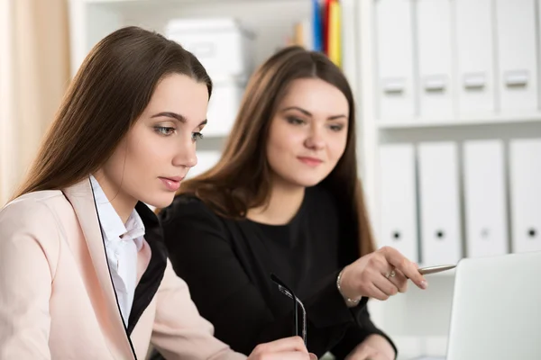 Dwie kobiety siedzącej w biurze i patrząc na monitor laptopa — Zdjęcie stockowe