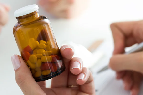 Vista de cerca de la mano del médico femenino sosteniendo la botella con pastillas —  Fotos de Stock