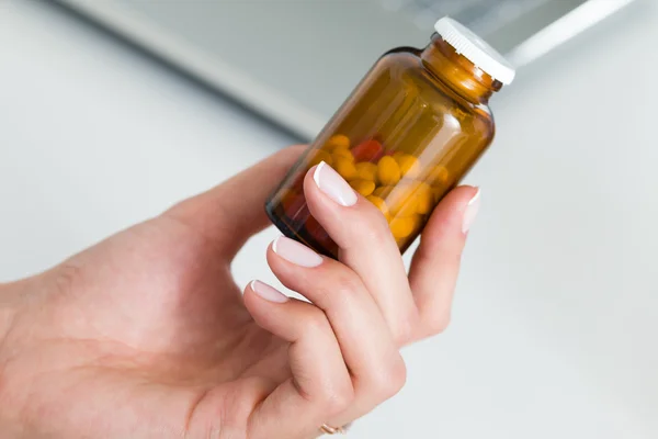 Visão de close-up do médico fêmea mão segurando garrafa com pílulas — Fotografia de Stock