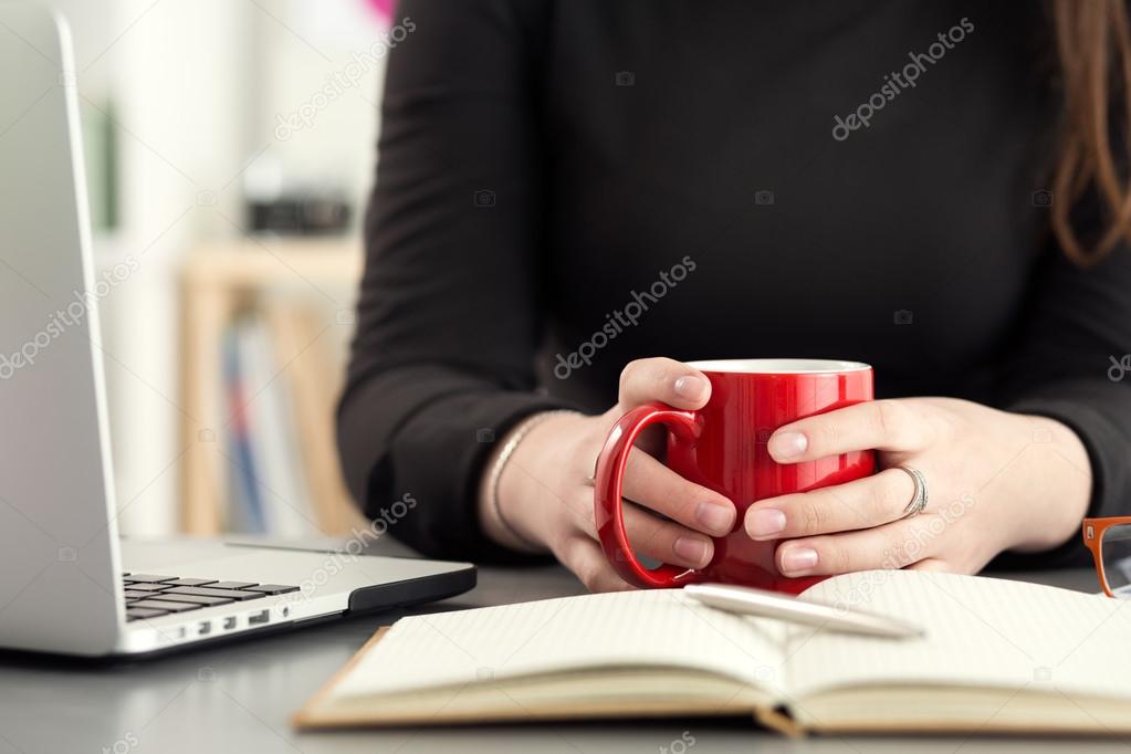 Female designers in office drinking morning tea or coffee