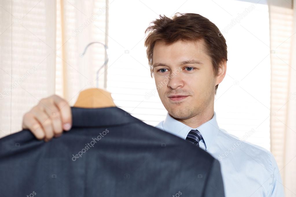 Business man holding his coat and looking at it ready to put it 