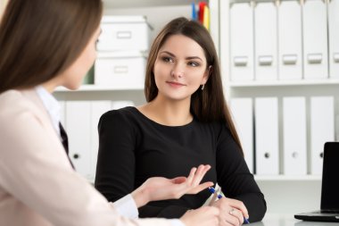 Ofiste oturan ve bazı soruları tartışan iki kadın.