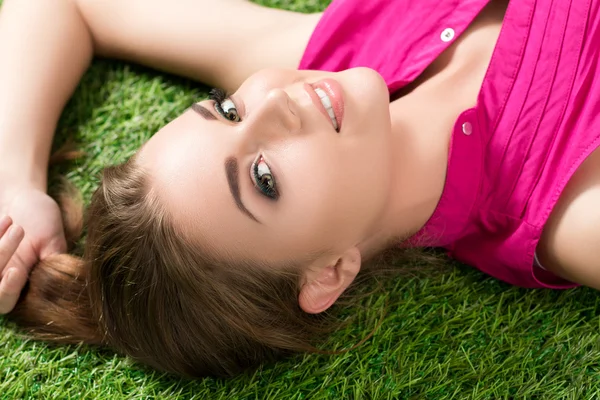 Giovane bella ragazza sdraiata sull'erba nel parco — Foto Stock