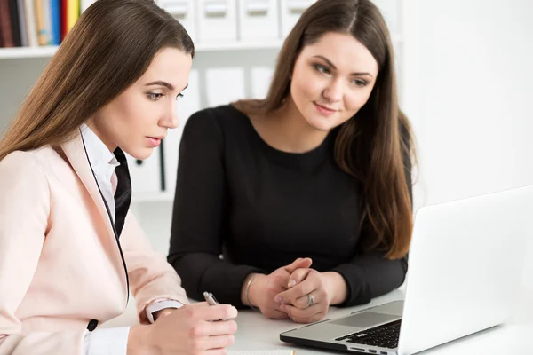 Dos mujeres sentadas en la oficina y mirando el monitor del portátil —  Fotos de Stock