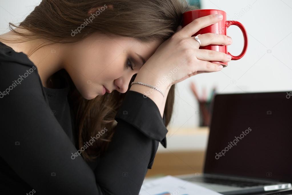 Tired female employee at workplace in office touching her head