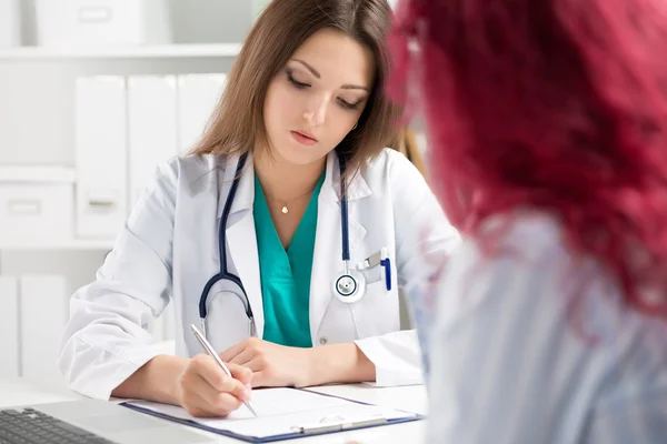 Médico preenchendo formulário médico durante a consulta do paciente — Fotografia de Stock