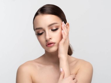 Genç güzel bir kadın yüzüne dokunuyor.