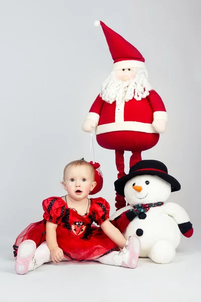 Little girl sitting on the floor near christmas toys — Stock Photo, Image