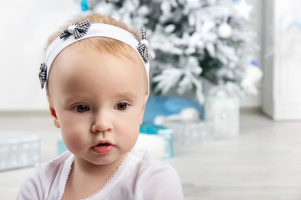 Little girl in front of christmas tree looking sideways — Stock Photo, Image