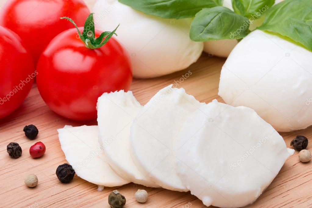 Mozzarella, tomatoes and basil leaves lying on table