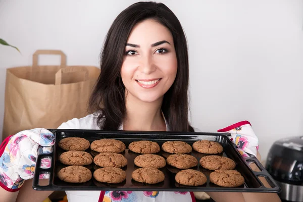 Schöne Frau hält heiße Bratpfanne mit Keksen — Stockfoto